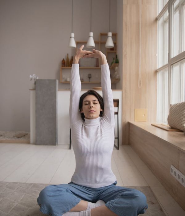 Woman in a calm breathing pose with amber light tones.